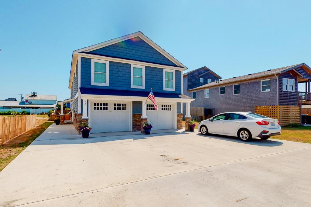 a blue house with a car parked in a driveway at Seas the Day OBX in Kitty Hawk Beach