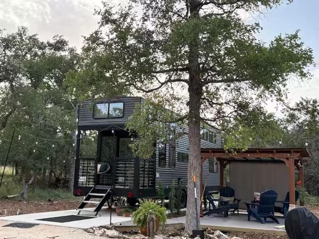 a tiny house with a porch and a tree at Bumblebee - Luxury Destination Trailer in Canyon Lake
