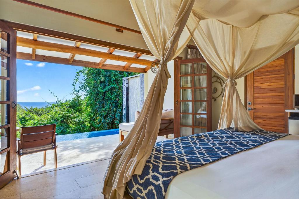a bedroom with a bed and a view of the ocean at Ocio Villas Mal Pais in Santa Teresa Beach