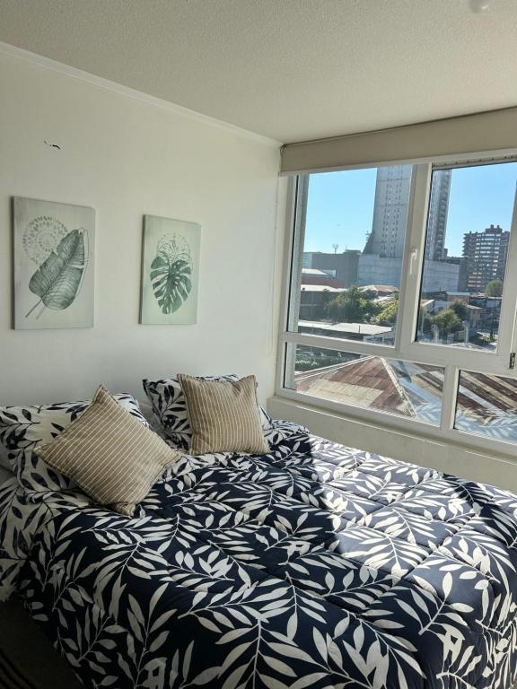 a bedroom with a bed and a large window at Edificio león Gallo in Temuco