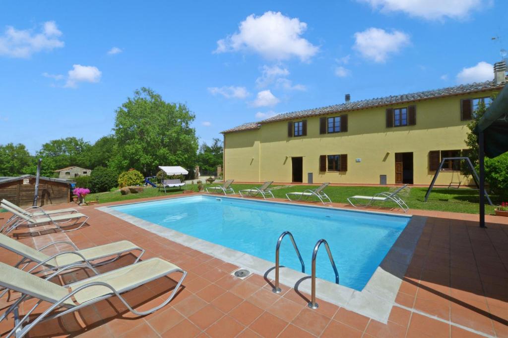 a pool in front of a building with chairs and a house at Casa Sofi - Happy Rentals in Monticiano
