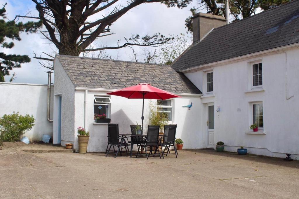 a table and chairs with an umbrella in front of a house at The Dairy Nolans organic farm in Ramsgrange