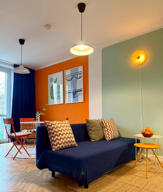 a living room with a blue couch and an orange wall at Lovely Jubbly Apartment in Krakow