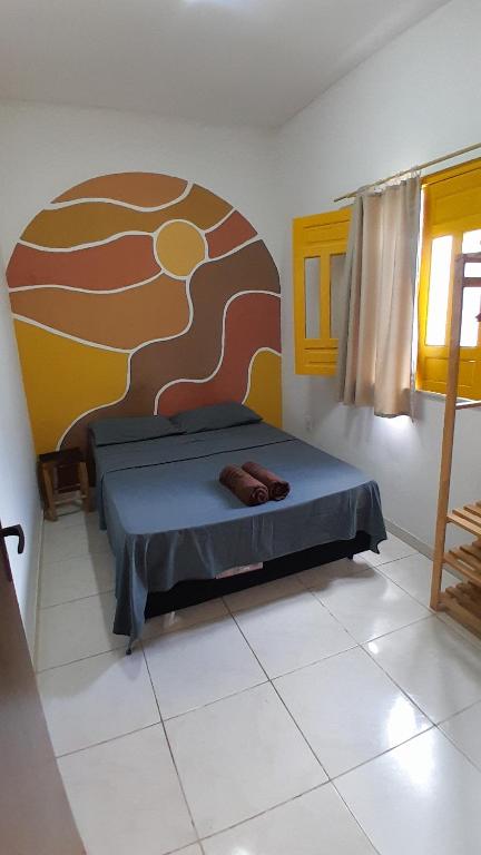 a bedroom with a bed with a painting on the wall at Casa Relva Suítes in Lençóis