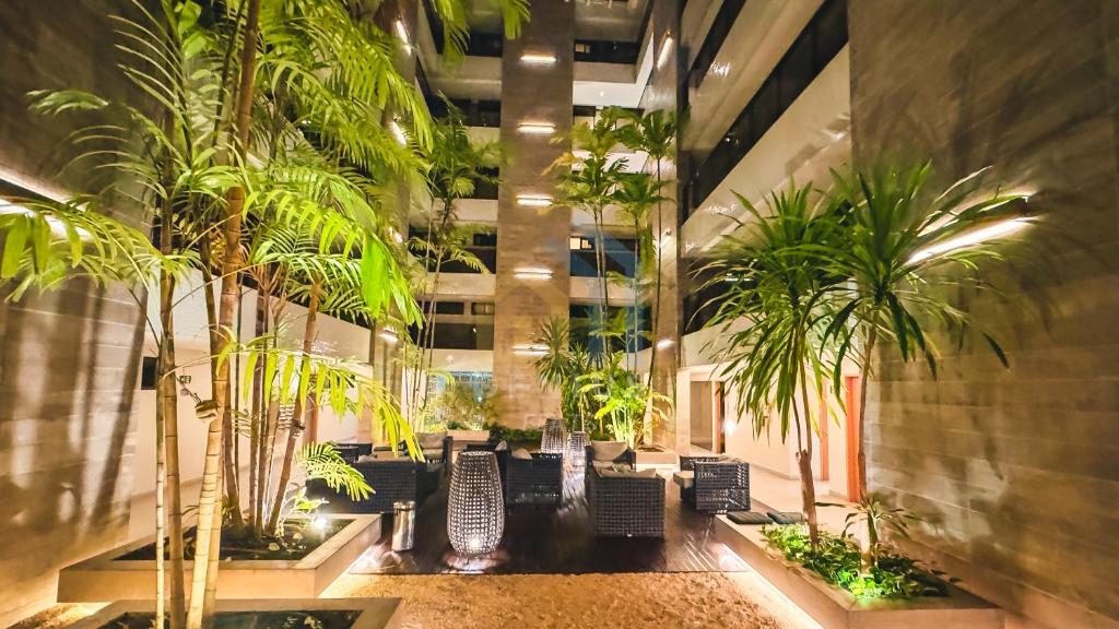 a lobby with chairs and palm trees in a building at Eco Summer Tambaú WB Genius Flats in João Pessoa