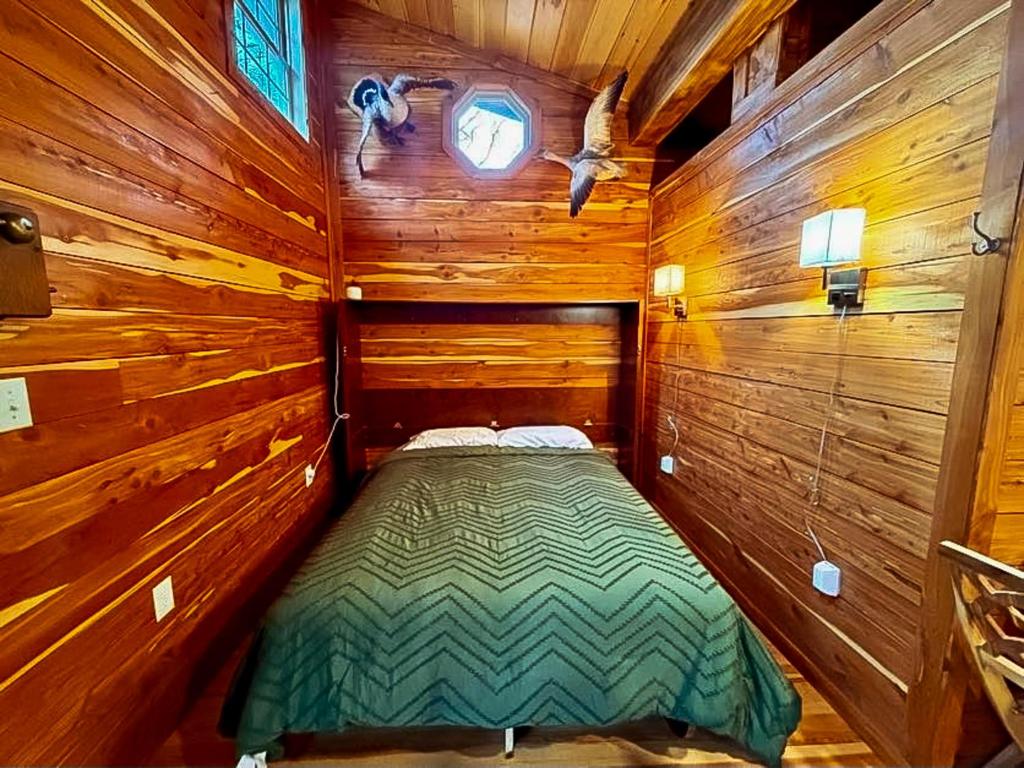 a small room with a bed in a wooden cabin at Treehouse by the Creek in Walland