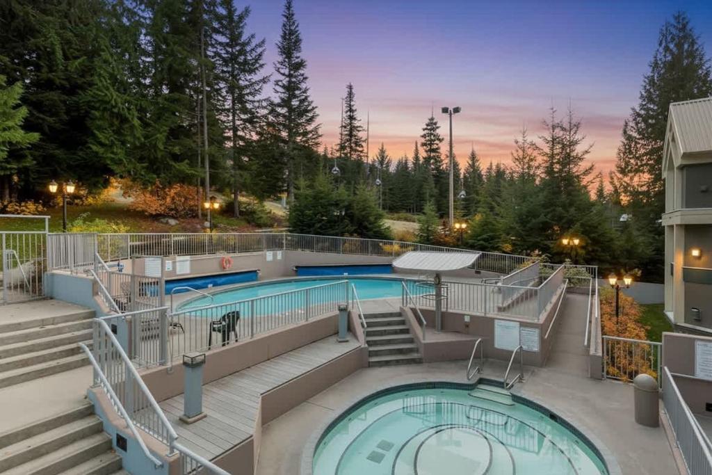 a pool with a deck and stairs next to a building at Woodrun Lodge 211 | Ski-In Ski-Out Condo w/ Heated Pool, Hot Tub, Parking, & Gym in Whistler