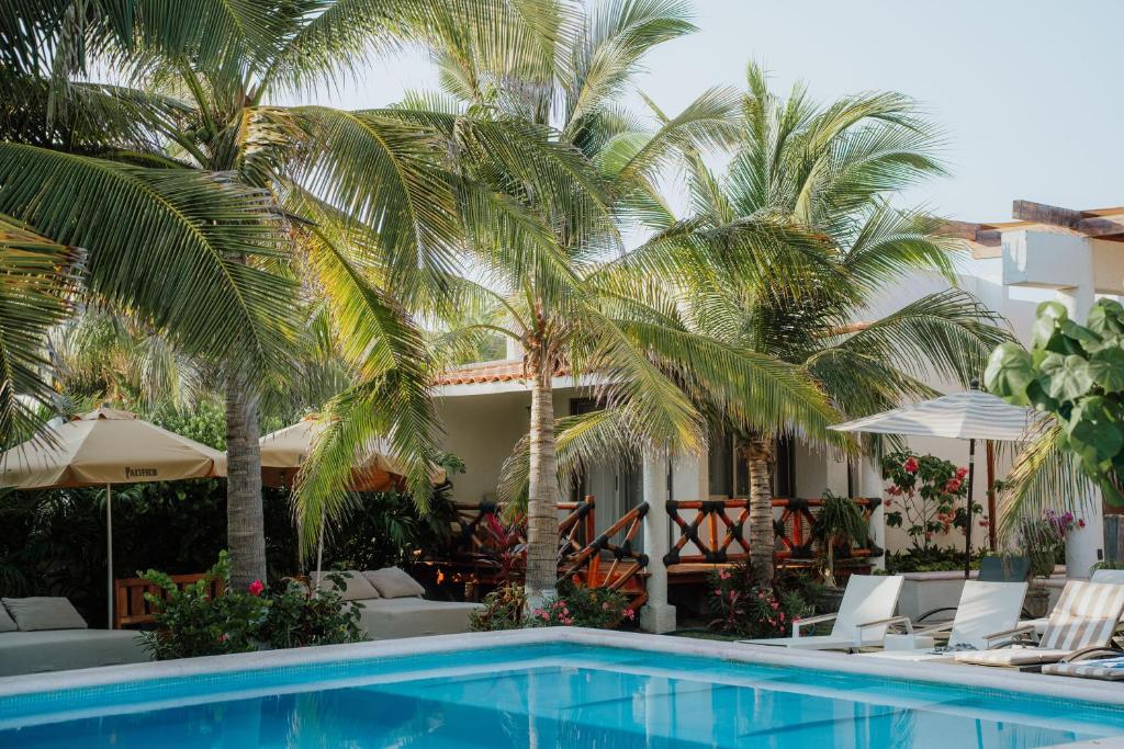 a pool in front of a hotel with palm trees at Villa Marena Hotel Boutique in Coyuca