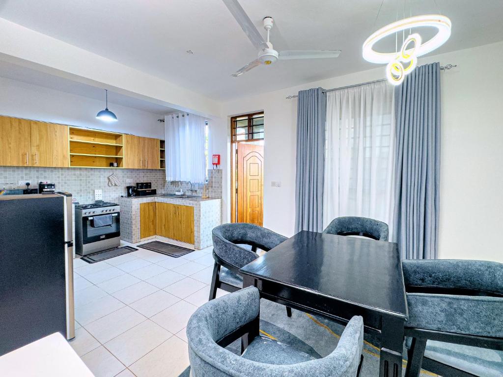 a kitchen and dining room with a black table and chairs at Diani hideouts in Kwale