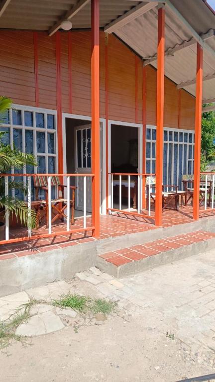 a building with orange pillars and tables and benches at Posada la Melosa in Guataquí