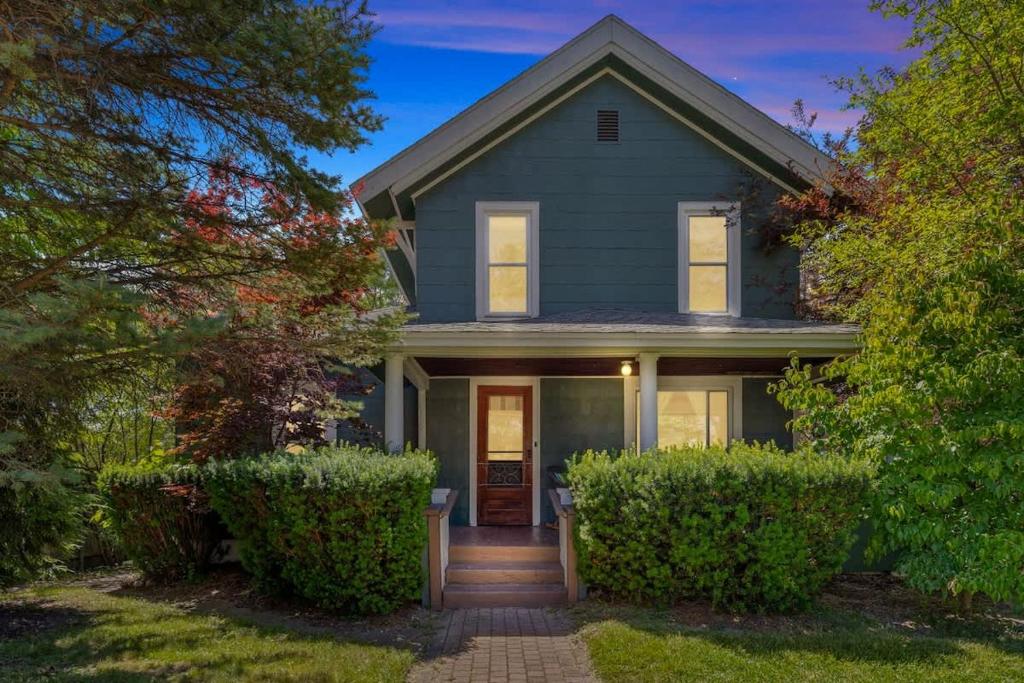 a gray house with a front door and trees at The Fourth Oak by Juniper Holiday + Home in Three Oaks