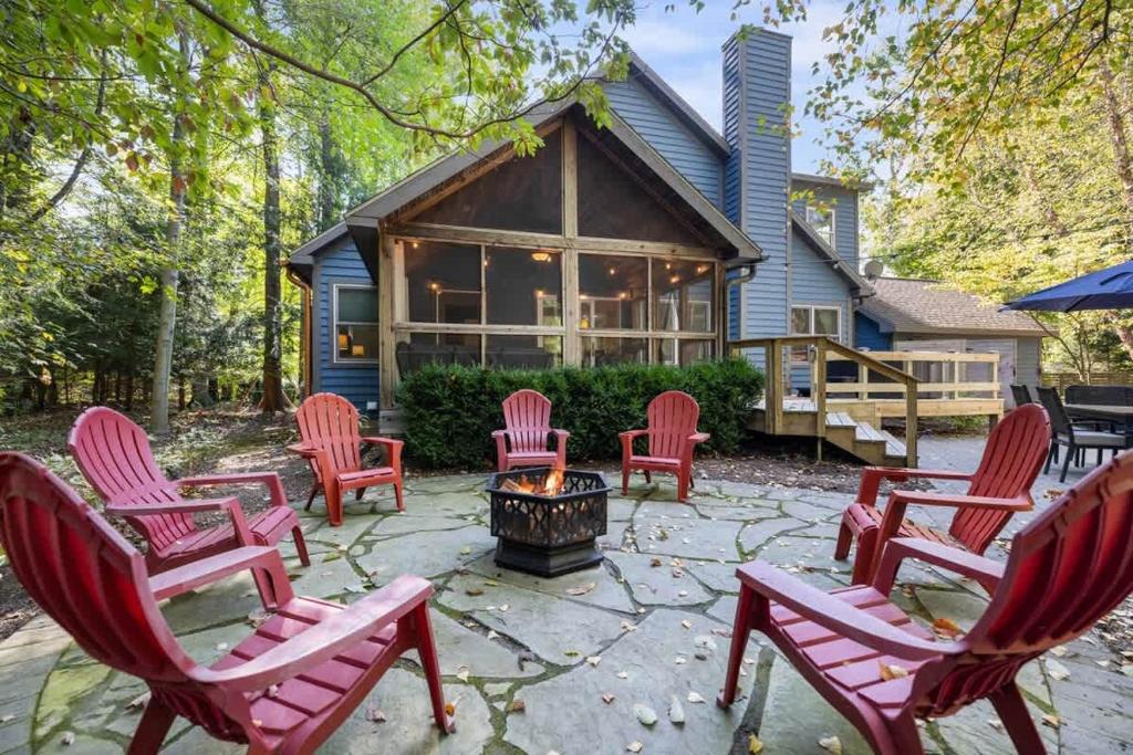 a group of red chairs around a fire pit in front of a house at Blue Beech Cottage in Union Pier