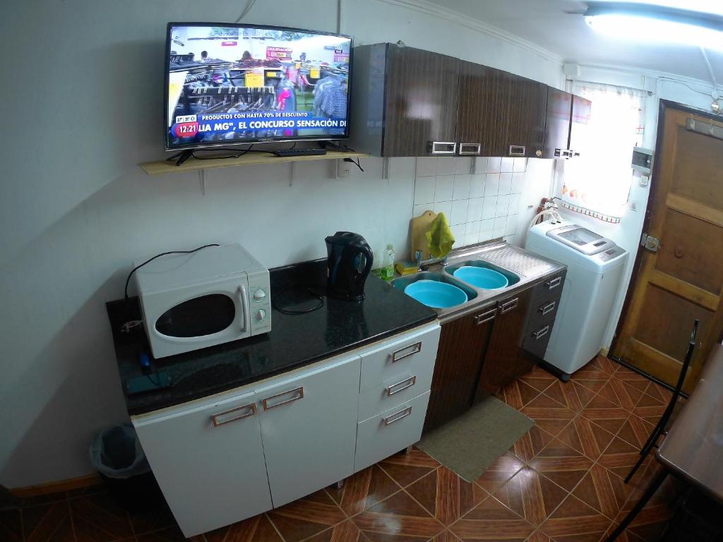 una pequeña cocina con fregadero y TV en la pared en Casita Independiente en Punta Arenas