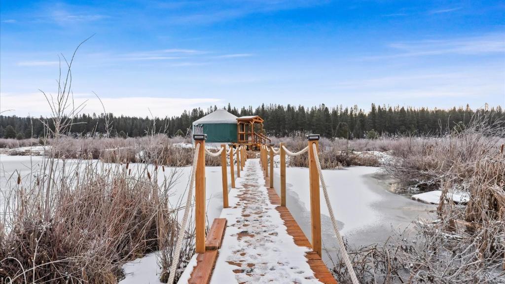a wooden walkway in a snowy field with a building at Yurt 2 - The Gold Miner in Idaho City
