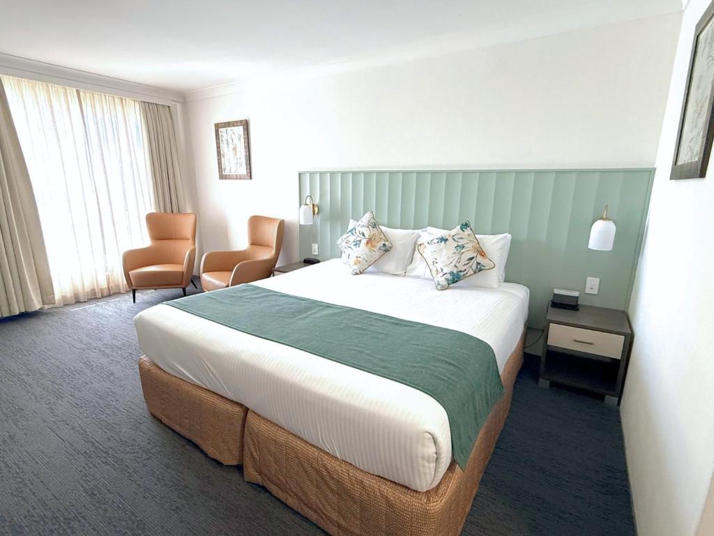 a hotel room with a large bed and a chair at Bathurst Motor Inn in Bathurst