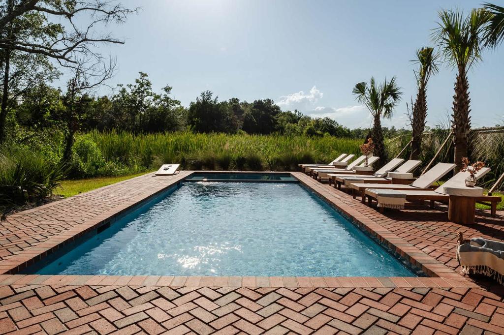 a swimming pool with chaise lounge chairs and a swimming pool at Modern Coastal Home with Heated Pool in Bay Saint Louis