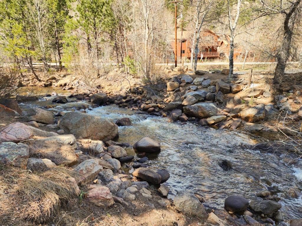 a river with rocks and trees and a house at Nicky's Resort in Estes Park