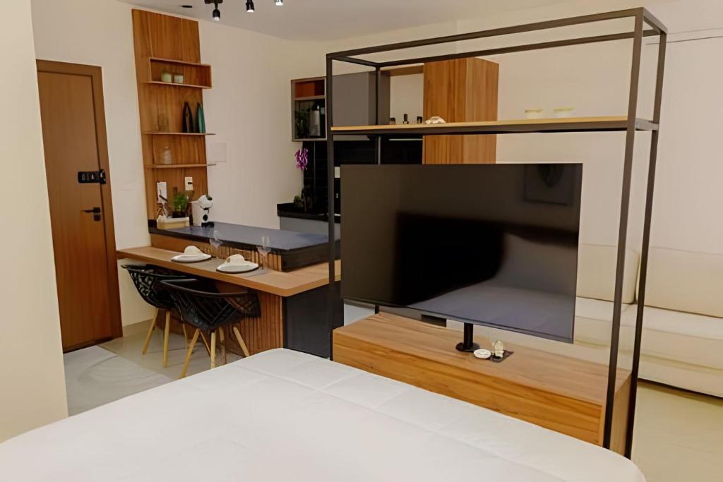 a bedroom with a bed and a desk with a large television at Studio Moderno com Internet e Garagem. in Três Corações