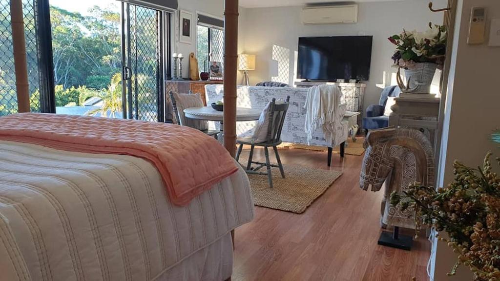 a bedroom with a bed and a living room with a television at Stylish Studio in Reedy Creek in Gold Coast