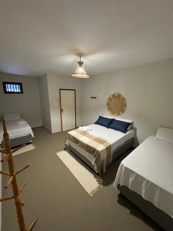 a bedroom with two beds and a chandelier at Pousada Raízzes in Amontada