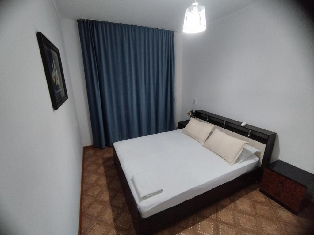 a bedroom with a white bed with a blue curtain at Мерей 1 in Qyzylorda
