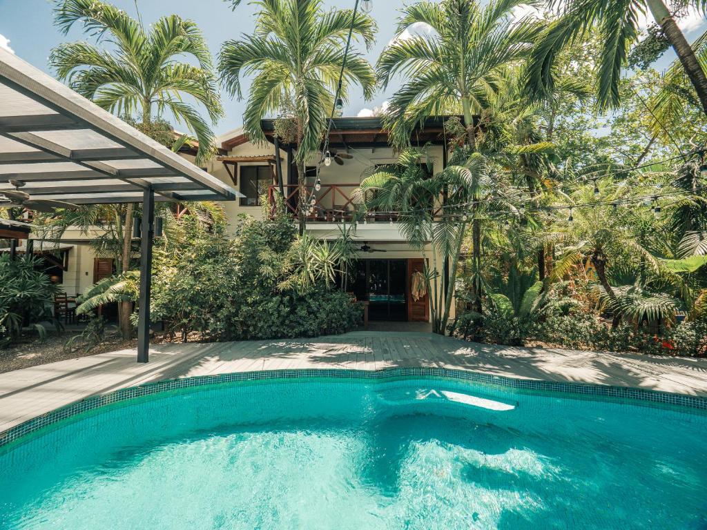 a swimming pool in front of a house with palm trees at Beach Heaven in Playa Guiones