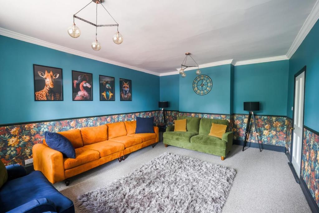 a living room with an orange couch and a green chair at 5 bed central home- beautiful modern in Witney
