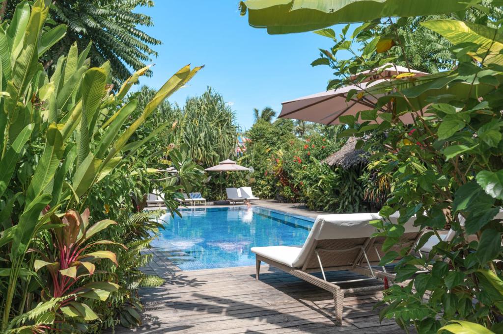 a swimming pool with two lounge chairs and an umbrella at Kajali Siargao in General Luna