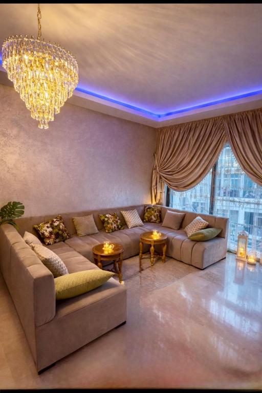 a living room with a couch and a chandelier at résidence avec piscine wifi et parking gratuit in Bouskoura