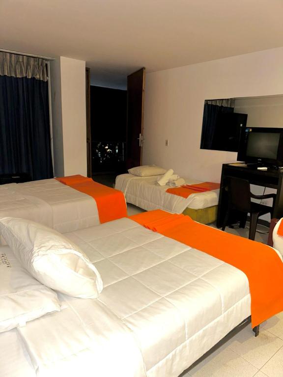 a hotel room with two beds and a desk at Santelmo Hotel Cali in Cali
