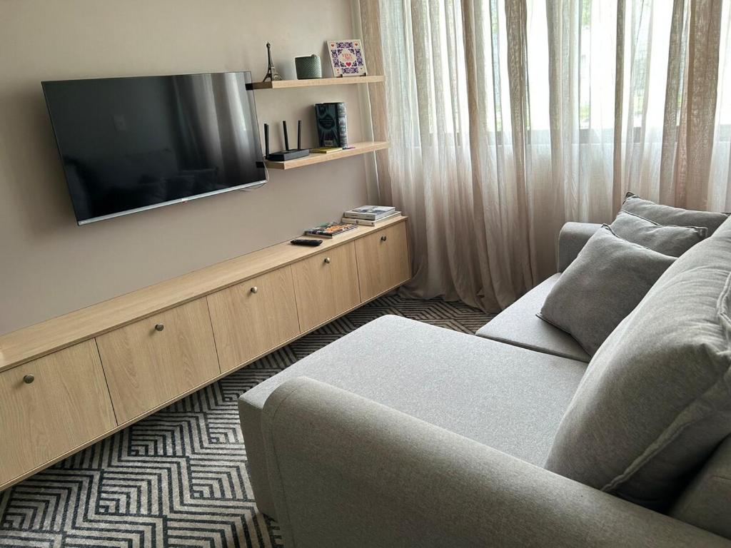 a living room with a couch and a flat screen tv at Apartamento confortável, calmo e bem localizado in Lucas do Rio Verde