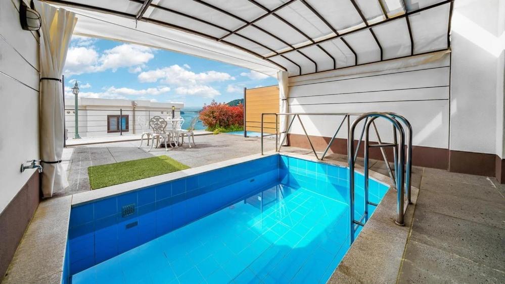 a swimming pool on the side of a house at Yeosu The Shine Blue Pool Villa in Yeosu