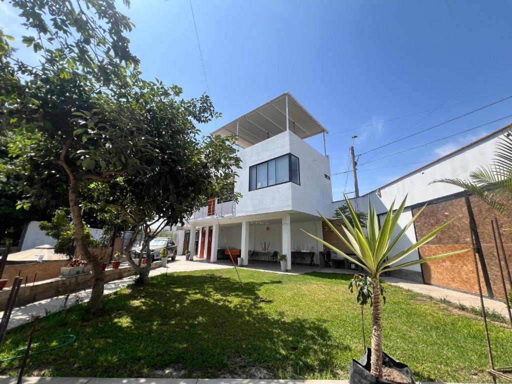 a white house with a palm tree in the yard at Estadía San Vicente in San Vicente de Cañete
