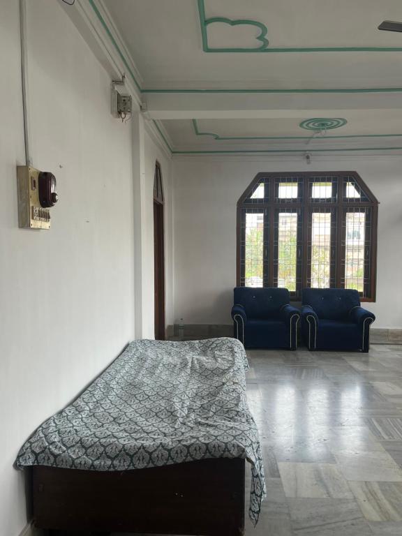 a room with a bed and two blue chairs at Aura house in Jorhat