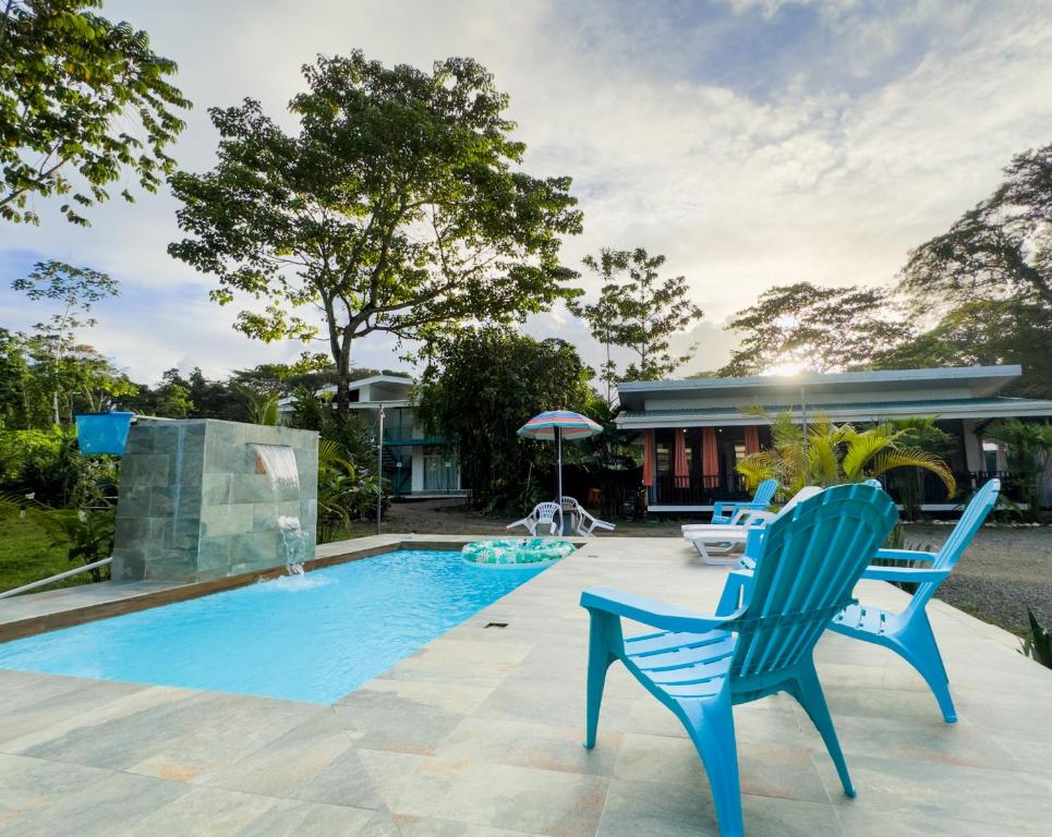 a swimming pool with two blue chairs and a house at La Jungla in Talamanca
