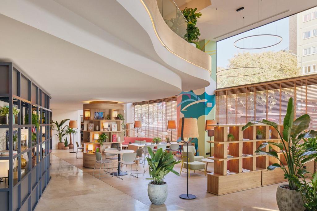a lobby with tables and chairs and plants at INNSiDE by Meliá Barcelona Apolo in Barcelona