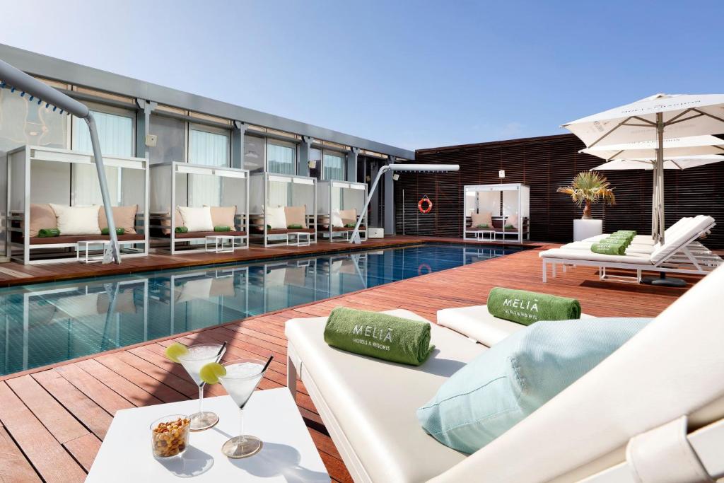a swimming pool with white lounge chairs and a hotel at Meliá Barcelona Sky 4 Sup in Barcelona