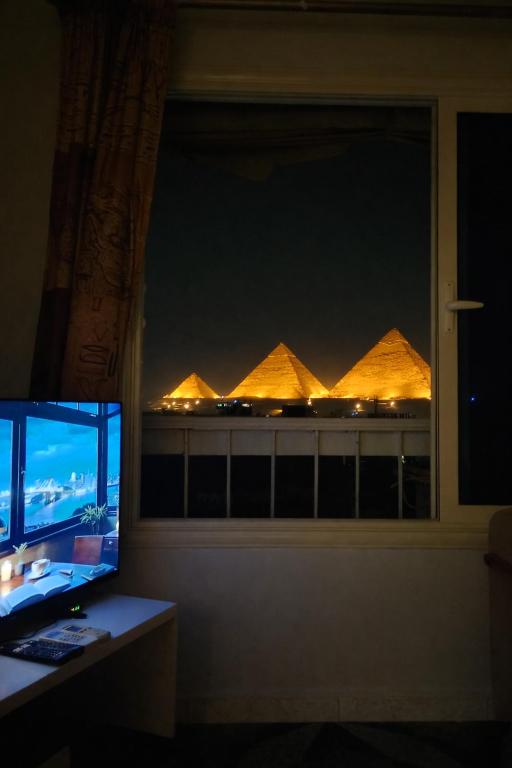 a window with a view of the pyramids at night at Kemet Pyramids Apartments in Cairo