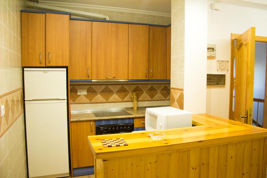 a kitchen with wooden cabinets and a white refrigerator at Apartmentos Corona in Cazorla