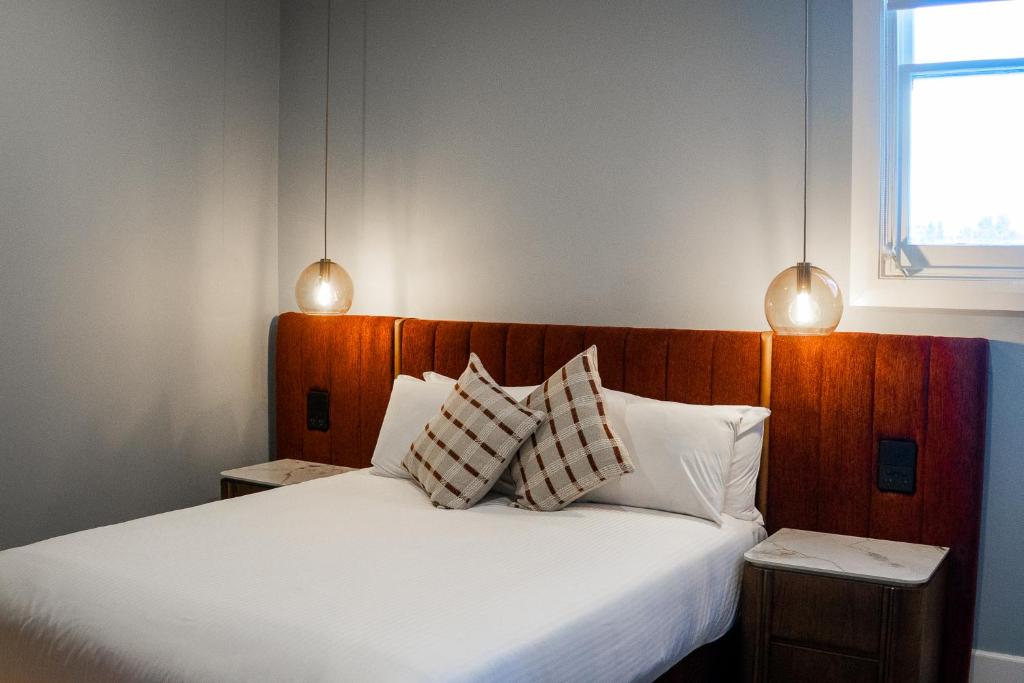 a bedroom with a large white bed with two pillows at Kincraig Hotel in Naracoorte