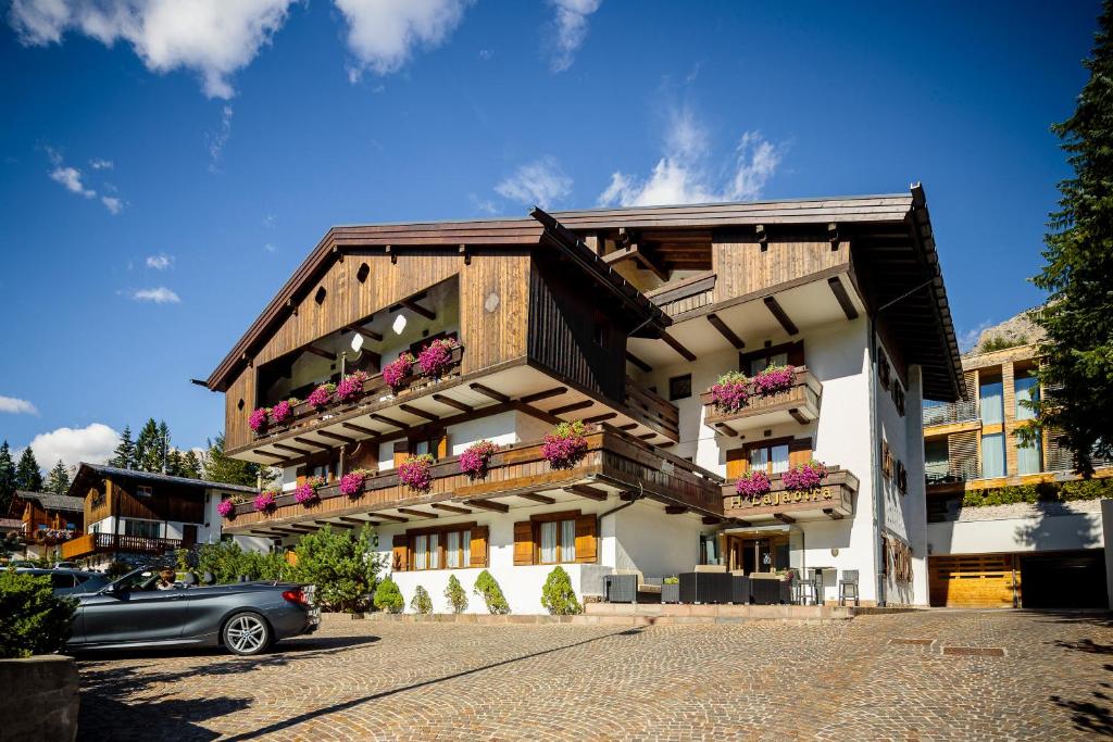 a building with flower boxes and a car parked in front at Hotel Lajadira & Spa in Cortina dʼAmpezzo