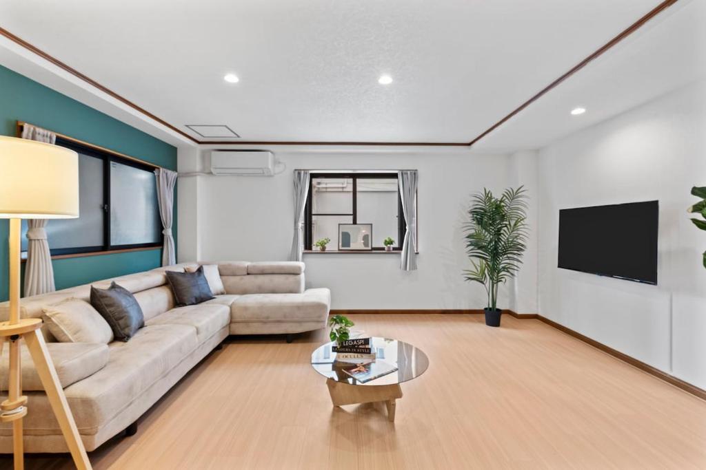 a living room with a couch and a tv at Crystal Jade Awaza2-4F in Wada