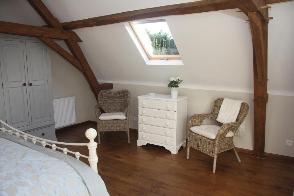 a bedroom with a bed and two chairs and a dresser at Les Bouts de Rallé Chambre d&#39;Hotes in Sainte-Osmane