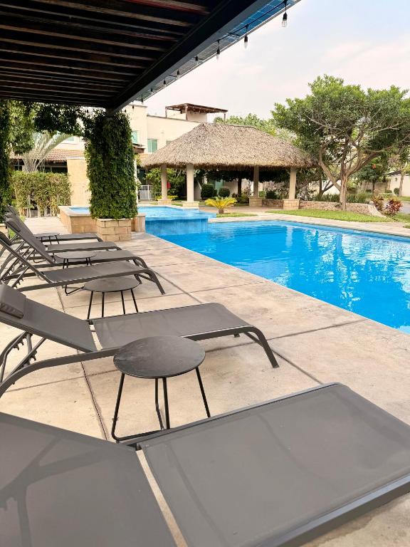 a swimming pool with lounge chairs next to a swimming pool at Casa con terraza frente alberca in Tezoyuca