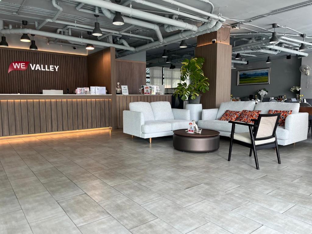 The reception lounge has white sofas, a lit front desk and an industrial-style ceiling.