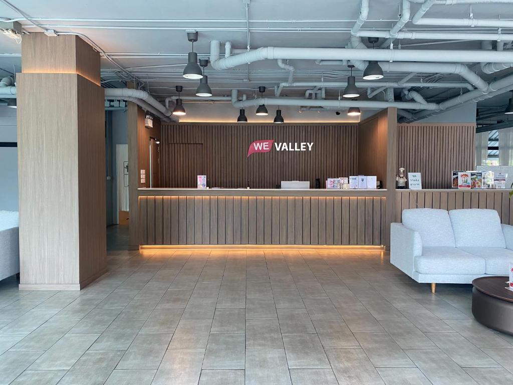 A modern reception lobby with a wood-paneled front desk and sofa seating.