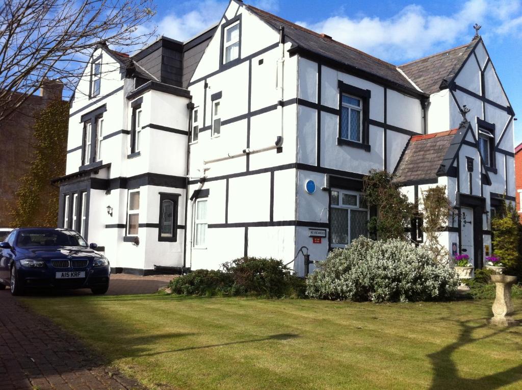 a black car parked in front of a white house at The Old Coach House in Blackpool