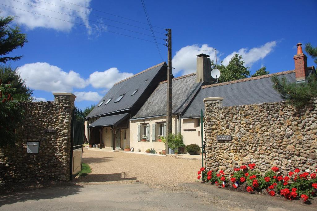 a stone building with red flowers in front of it at Les Bouts de Rallé Chambre d'Hotes in Sainte-Osmane