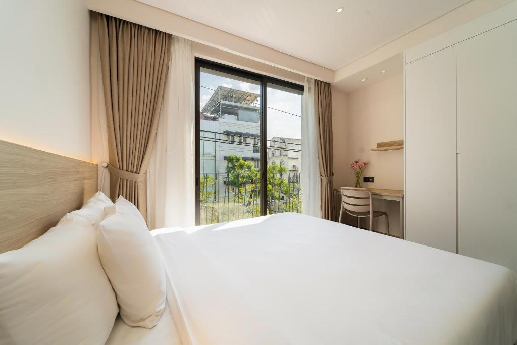 a bedroom with a white bed and a large window at Nina Sky Serviced Apartment in Ho Chi Minh City