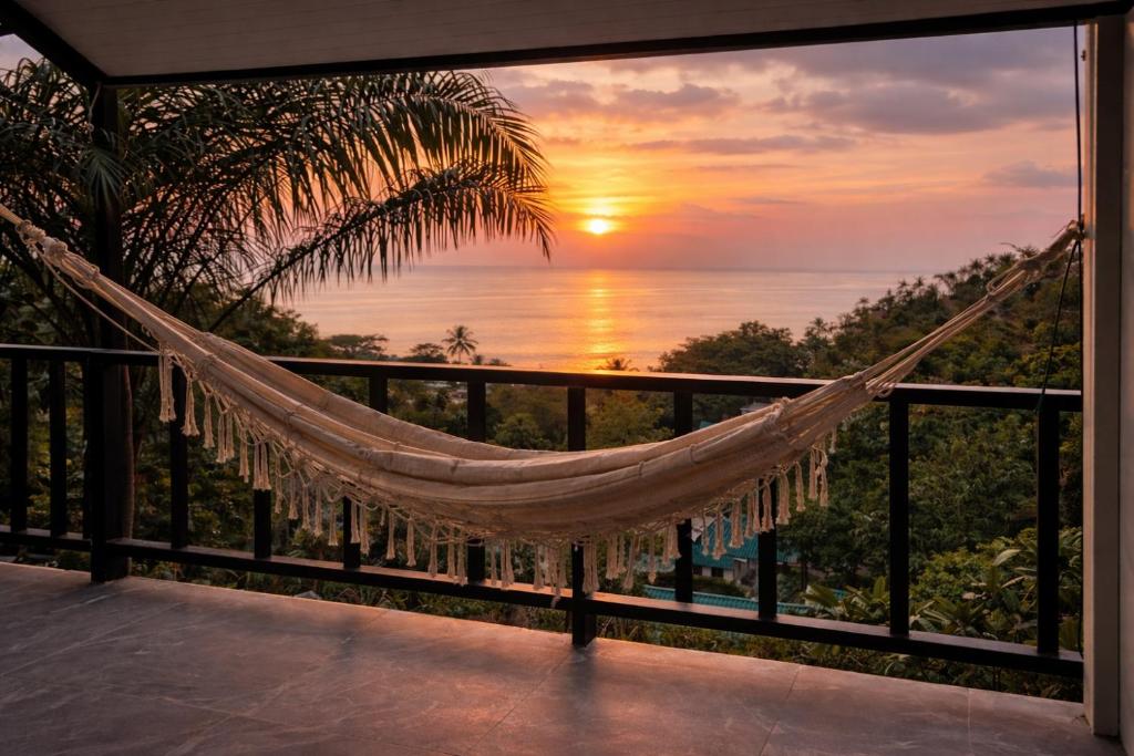a hammock on a balcony with a sunset at Panoramic Seaview New Bungalow in Salad Beach